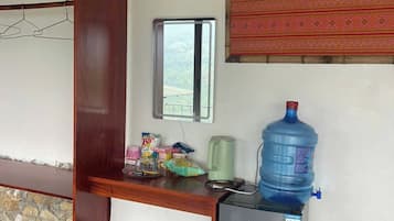 A compact kitchen with a refrigerator, a water dispenser, and a small table.