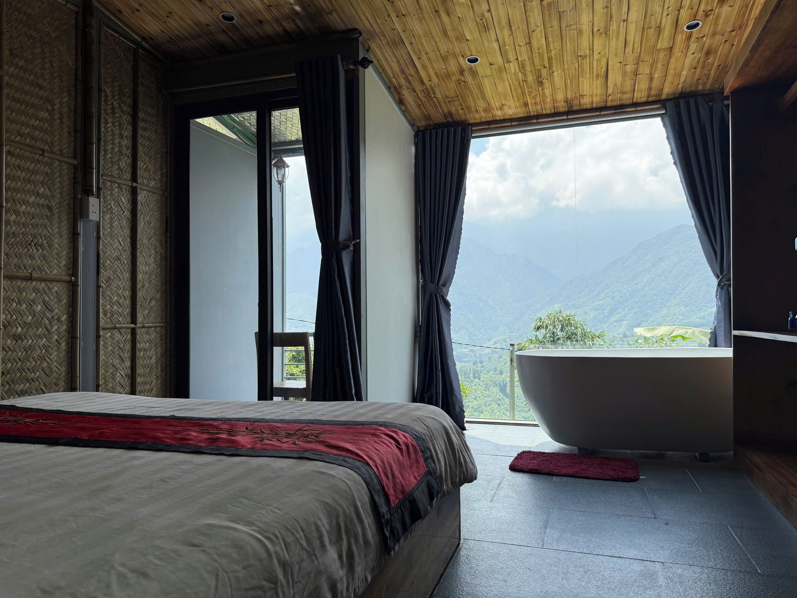 A bedroom with a large bed, a bathtub, and a view of mountains.