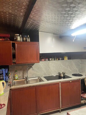 Una cucina con mobili in legno, un lavello, un fornello e un soffitto con motivo geometrico.