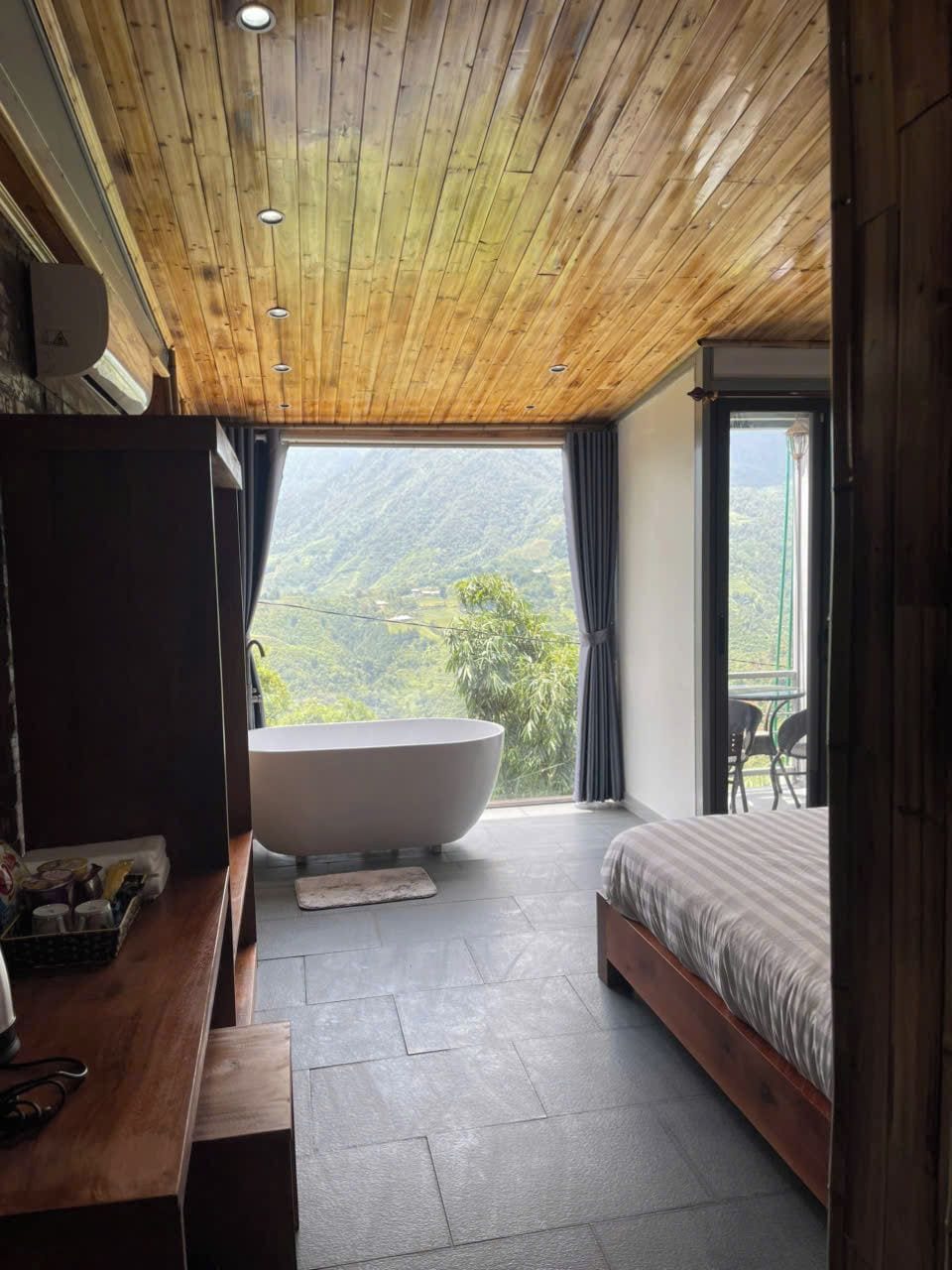 Un dormitorio con una bañera grande, una cama y vistas a un paisaje montañoso.