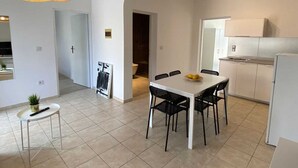 Una cocina moderna con armarios blancos, una mesa de comedor con sillas y una lámpara colgante.