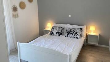 A bed with white bedding, two bedside lamps, and a wall with three circular wall art pieces.