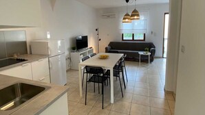 Una cocina compacta con comedor, un sofá y un televisor.