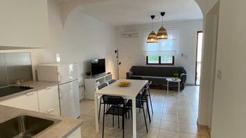 A compact kitchen with a dining area, a sofa, and a TV.