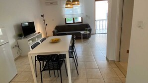 Una cocina moderna con una mesa de comedor, sillas, un televisor y un sofá al fondo.