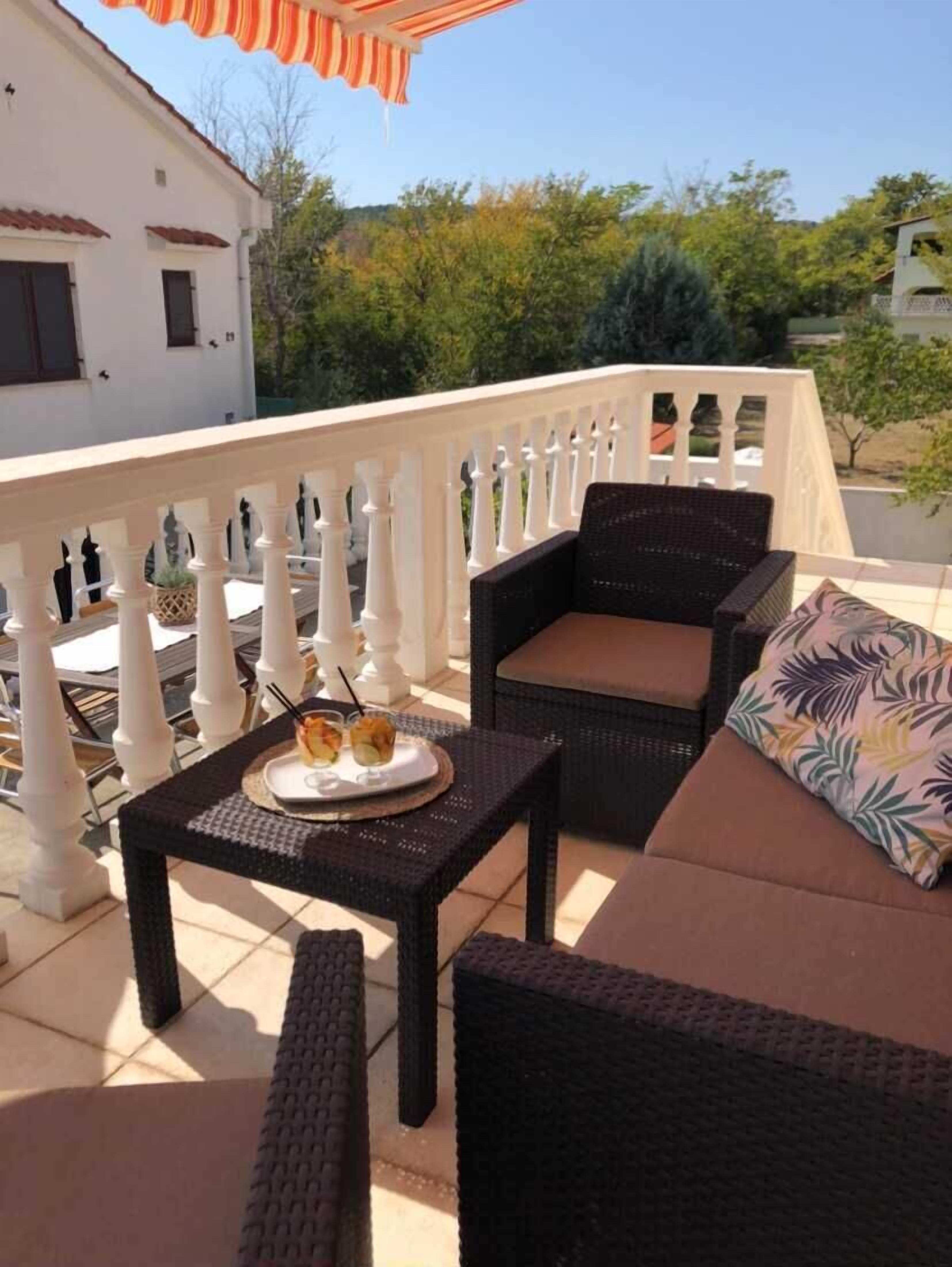 Ein Balkon mit Korbmöbeln, einem Tisch mit Speisen und einem weißen Geländer.