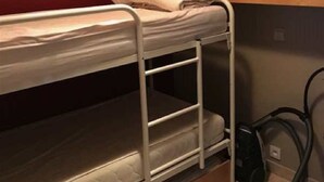 A bunk bed with a mattress and pillows, a vacuum cleaner, and wooden cabinets in a room. - Scorpio B 902 (Nieuwpoort)