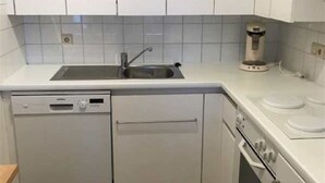 A kitchen with white cabinets, a dishwasher, an oven, and a coffee maker. - Scorpio B 902 (Nieuwpoort)