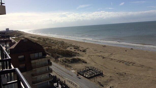 A beach view from a balcony with a parking area and a building in the foreground. - Scorpio B 902 (Nieuwpoort)