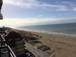 A beach view from a balcony with a parking area and a building in the foreground. - Scorpio B 902 (Nieuwpoort)