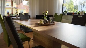 Un comedor con una mesa de madera, sillas verdes y plantas en macetas.