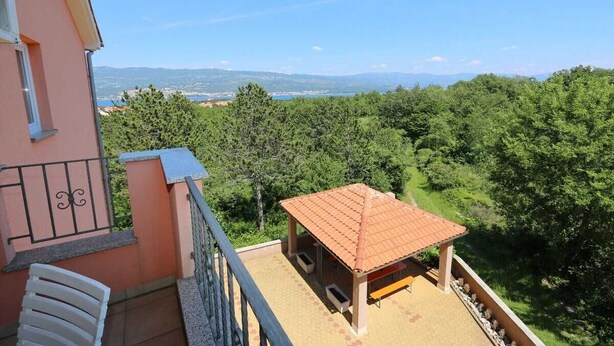 Ein Balkon mit Blick auf einen Wald und ferne Berge.