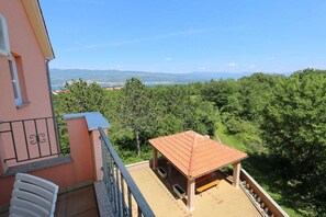 Un balcon donnant sur une forêt et des montagnes lointaines.