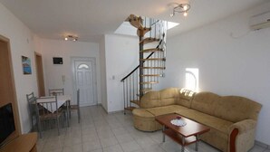 Ein Wohnzimmer mit einer Couch, einem Couchtisch, einem Fernseher, einem Esstisch mit Stühlen und einer Wendeltreppe.