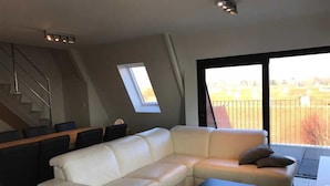 A modern living room with a white sectional sofa, a black coffee table, and a staircase. - Seabreeze 303 (Nieuwpoort)