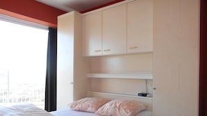 Un dormitorio con cama, ventana y armario.