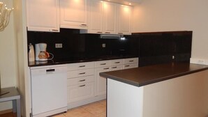 A kitchen with white cabinets, a black countertop, and a built-in oven. - Marco Polo 0102 (Nieuwpoort)