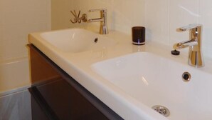 A modern bathroom with two sinks, a glass shelf, a shower, and a mirror. - Marco Polo 0102 (Nieuwpoort)