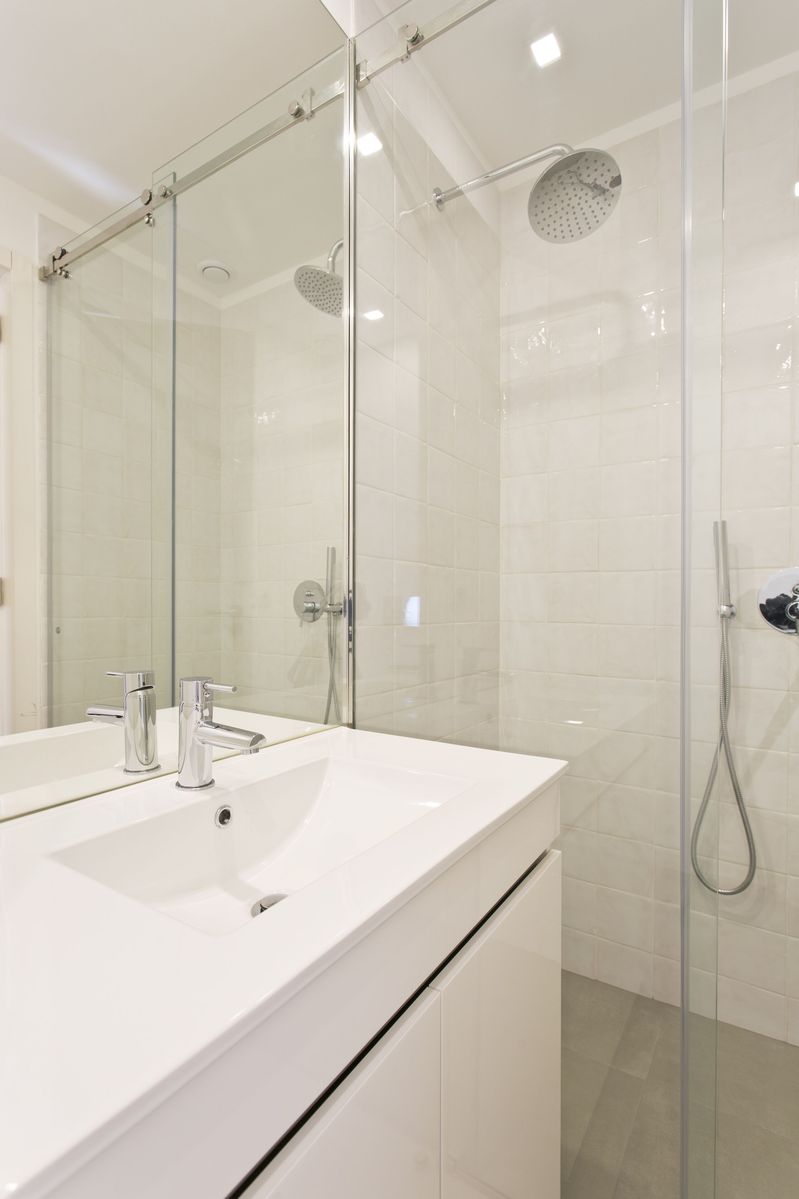 A modern bathroom with a glass-enclosed shower, a white sink, and chrome fixtures.