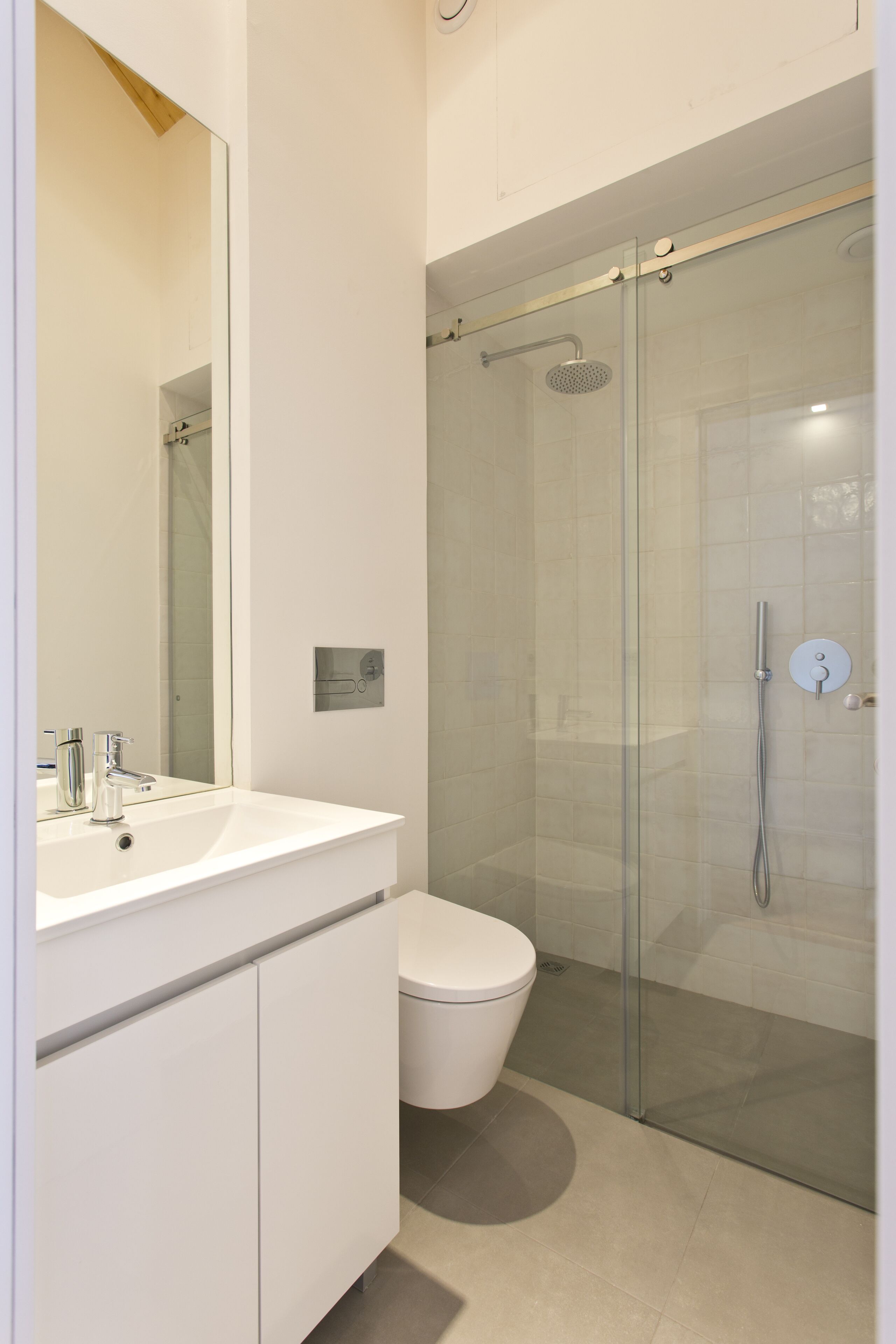 Une salle de bain moderne avec une douche à parois de verre, un lavabo blanc et des toilettes.