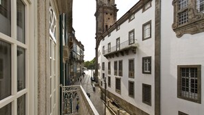 Una calle estrecha flanqueada por edificios, con balcones y una torre al fondo.