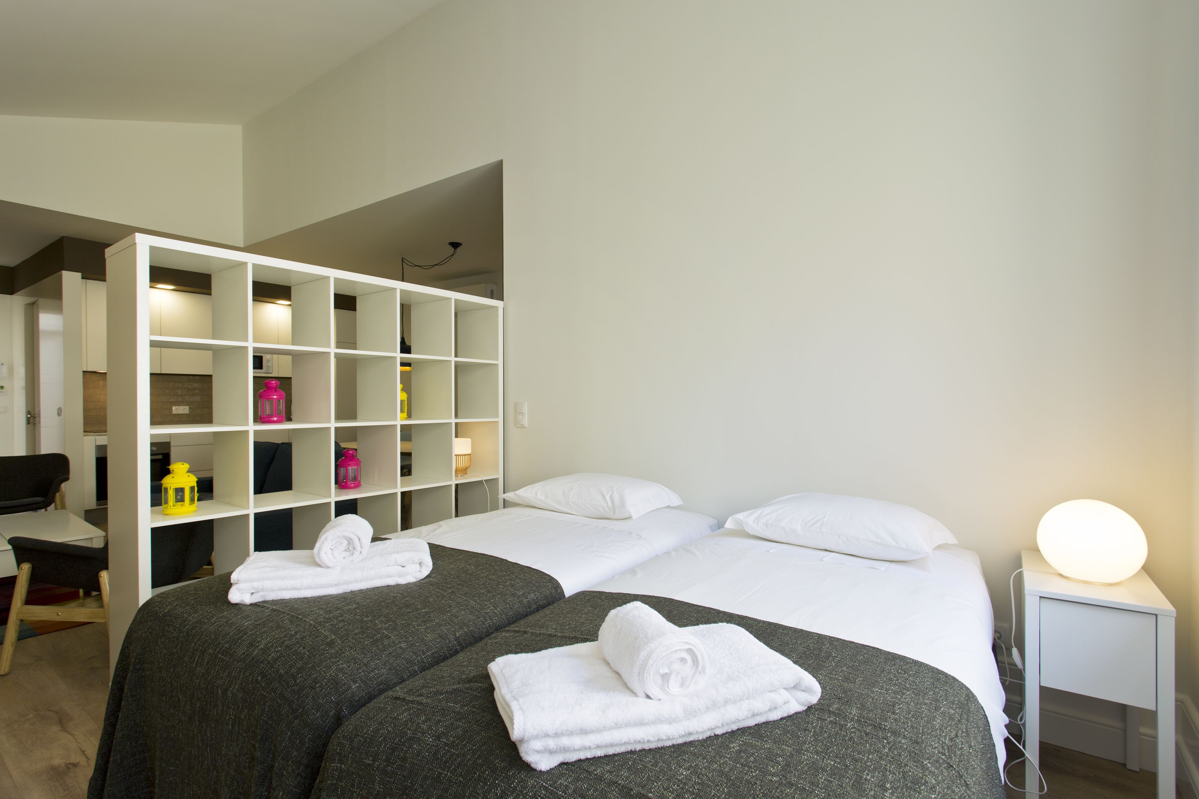 Een hotelkamer met twee bedden, een bureau en een wit wandrek.