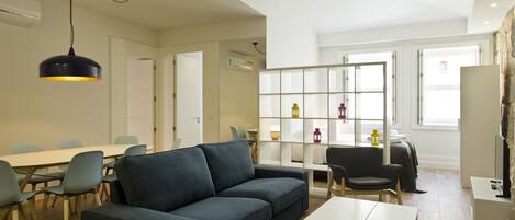 Ein modernes Wohnzimmer mit einer Couch, Sesseln, einem Esstisch und einem Bücherregal.