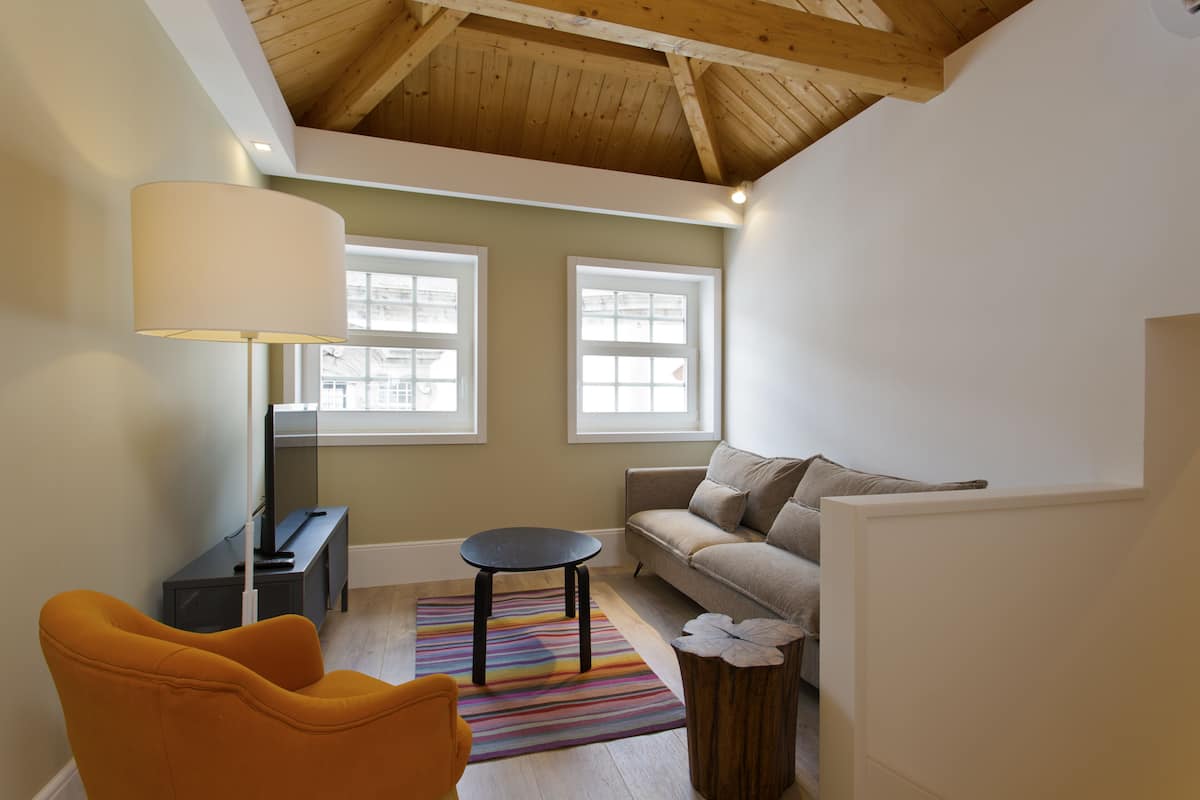 A cozy living room with a sofa, a small round table, a lamp, and a colorful rug.