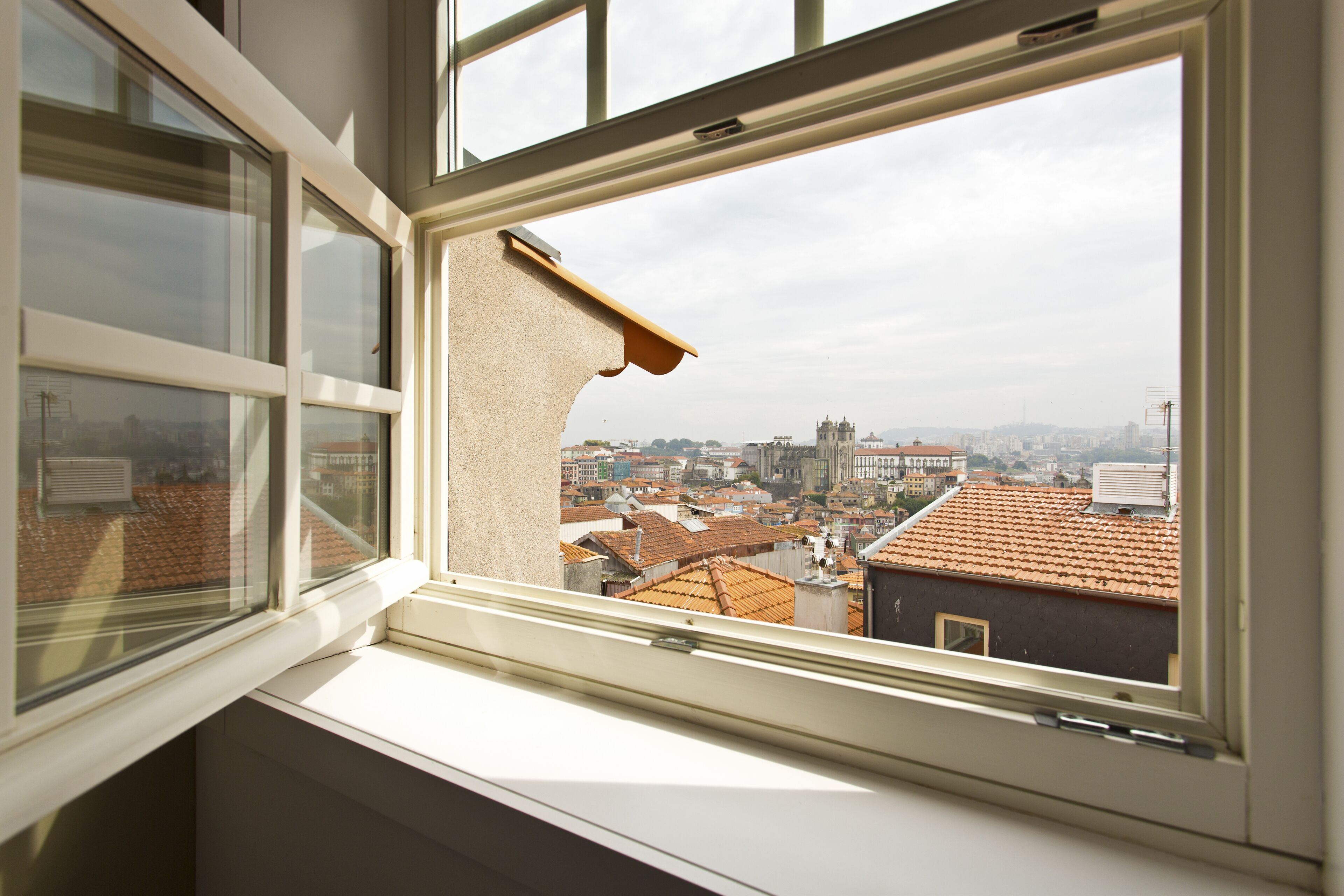 A window with a view of a cityscape, including buildings and a castle-like structure.