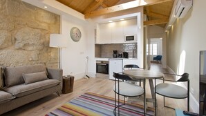 Una cocina moderna con microondas, horno y cafetera. Hay un comedor con mesa y sillas, y un sofá en la sala de estar.