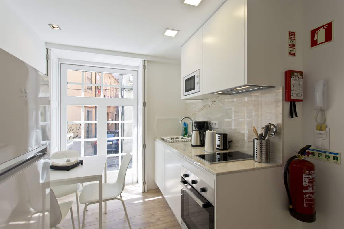 A modern kitchen with white cabinets, a microwave, a coffee maker, and a fire extinguisher.