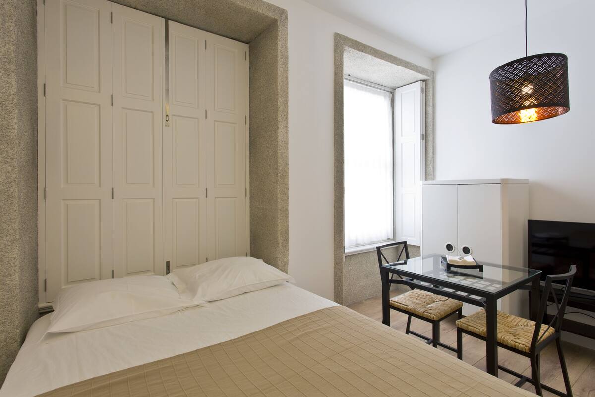 A bedroom with a bed, a desk, and a TV.