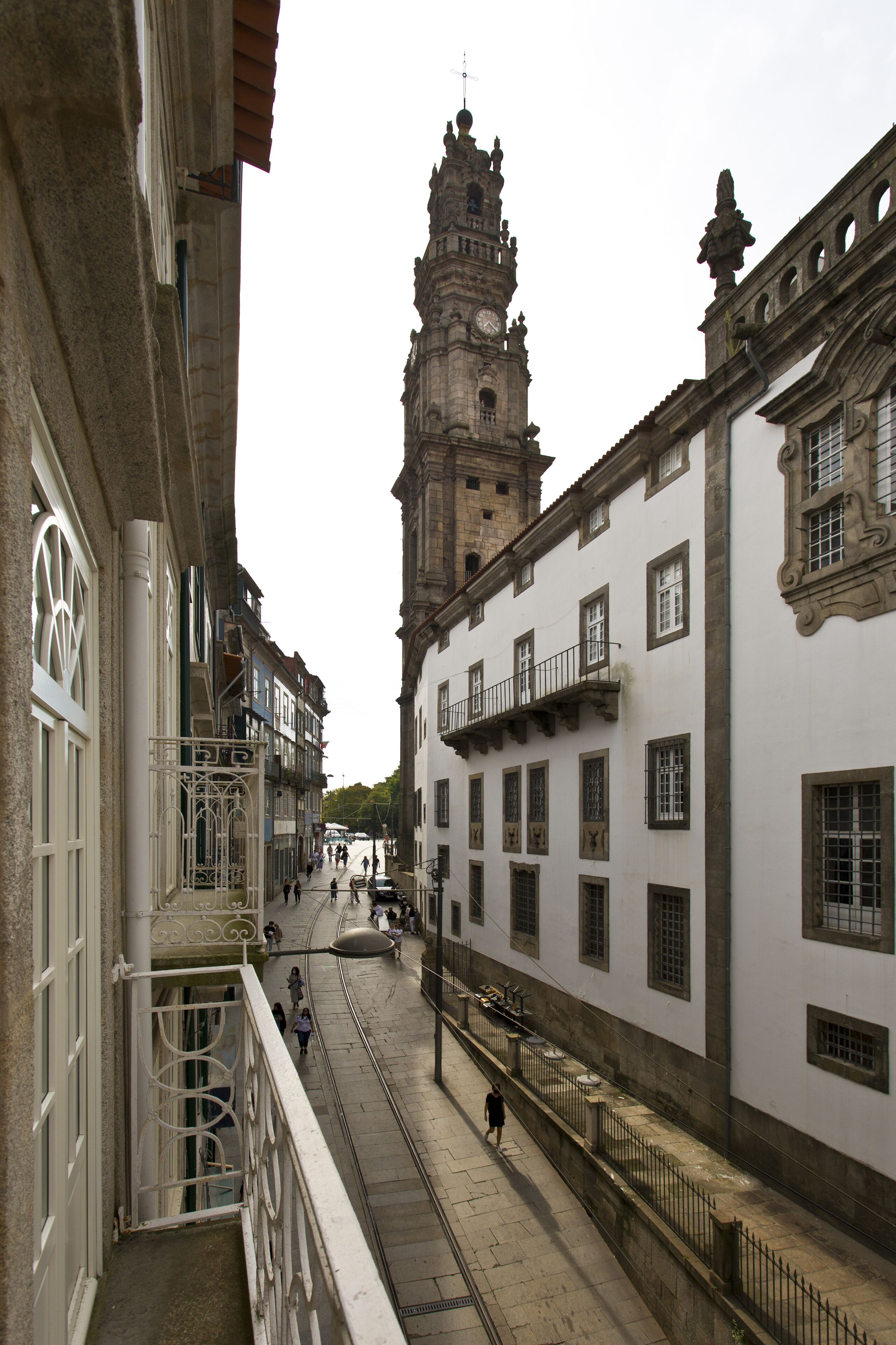 A historic street with a prominent tower, narrow pedestrian path, and traditional architecture.