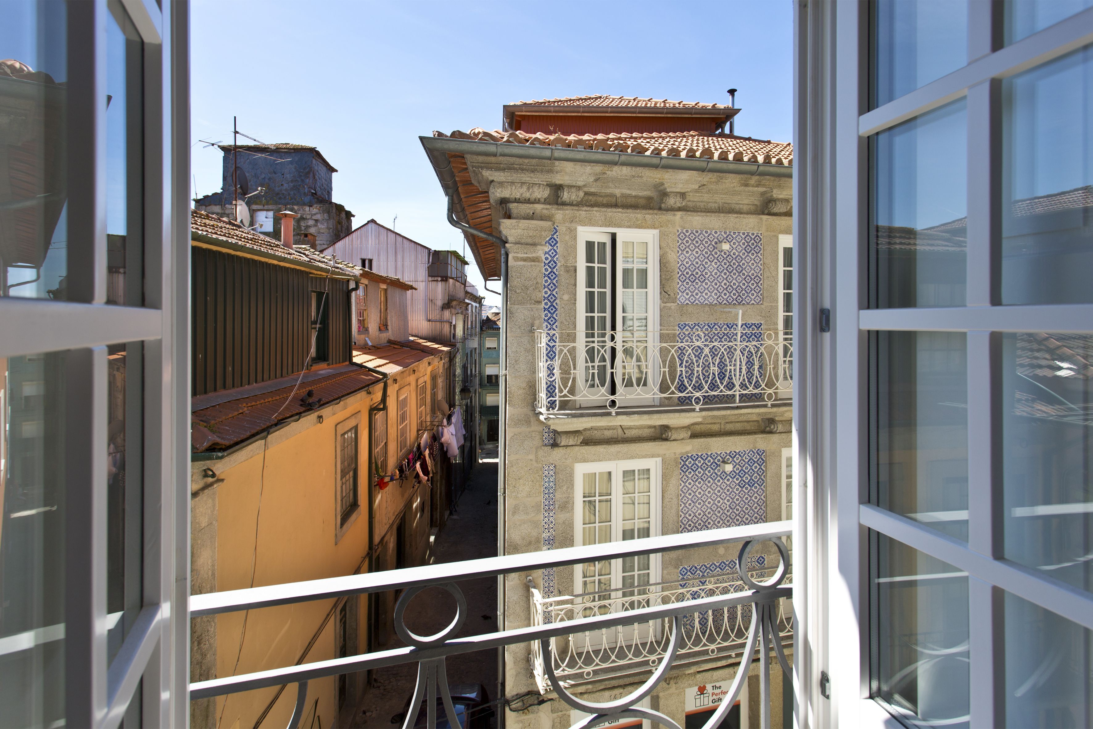 Una calle estrecha flanqueada por edificios, incluyendo uno con un balcón azulejado.
