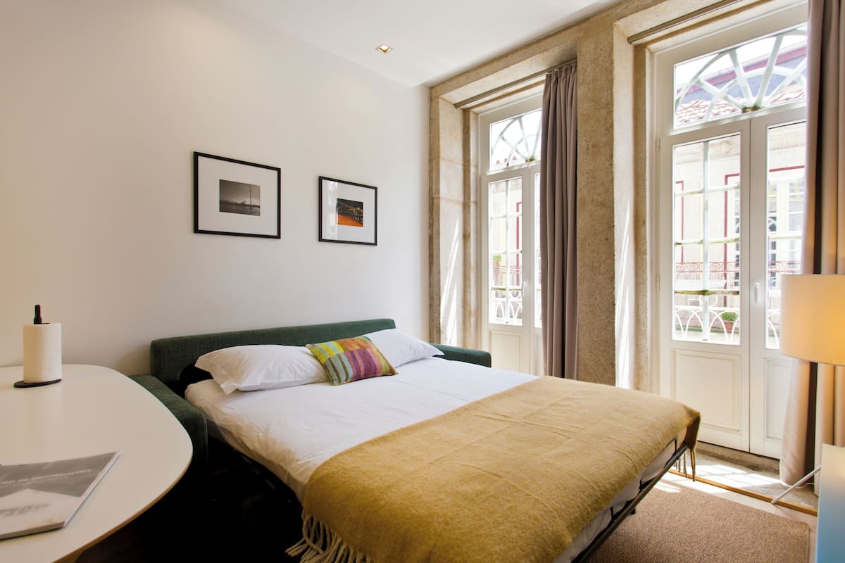 A hotel room with a bed, a round table, and two framed pictures on the wall.