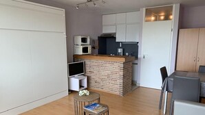 A compact living space with a kitchen, dining area, and a seating area with a small round table and chairs. - Nautillus 304 (Nieuwpoort)