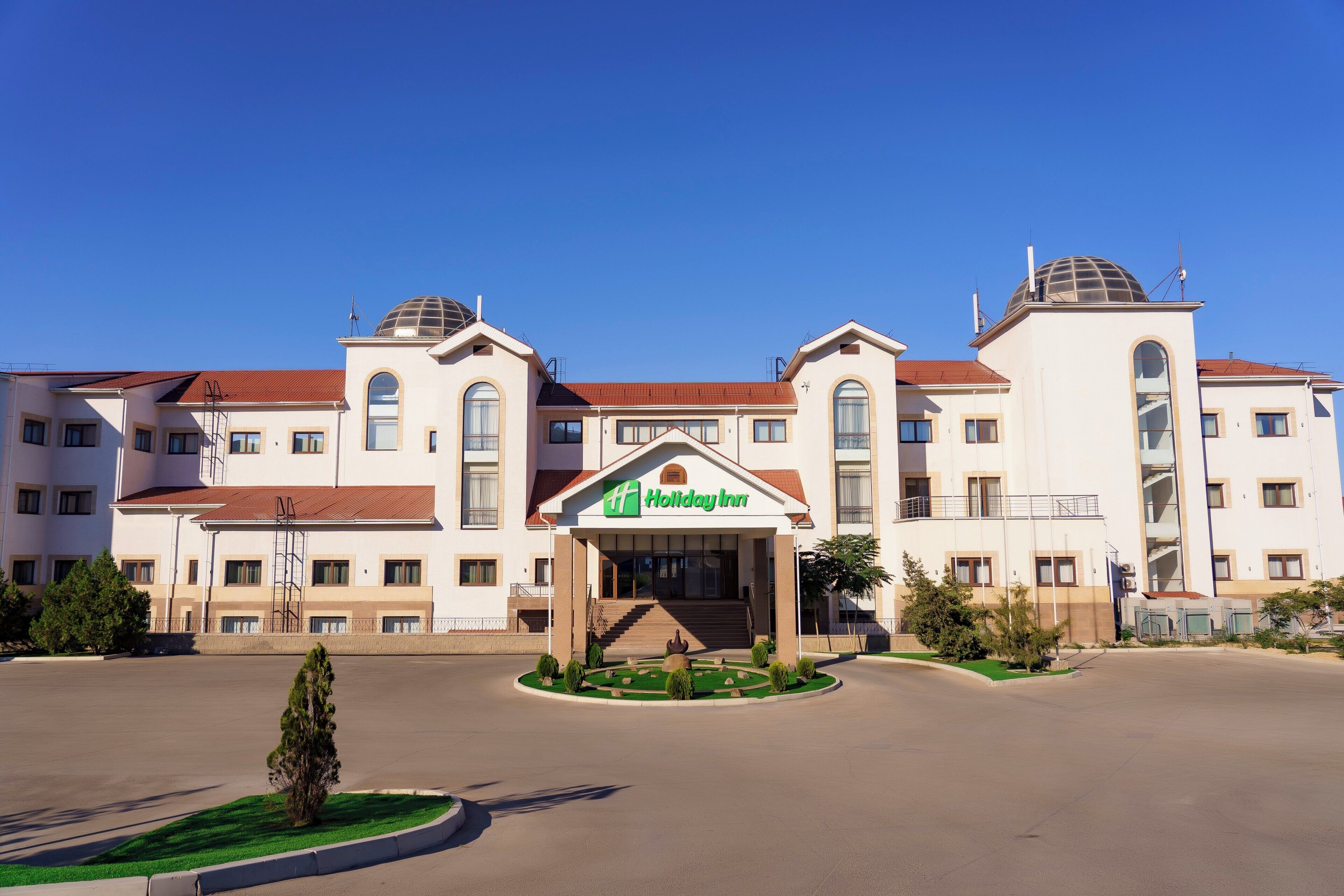 A Holiday Inn hotel with a central entrance, multiple floors, and a red-tiled roof.