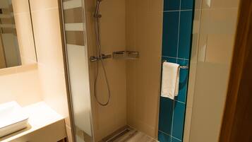Un baño moderno con cabina de ducha de vidrio, lavabo blanco y pared de acento azul.