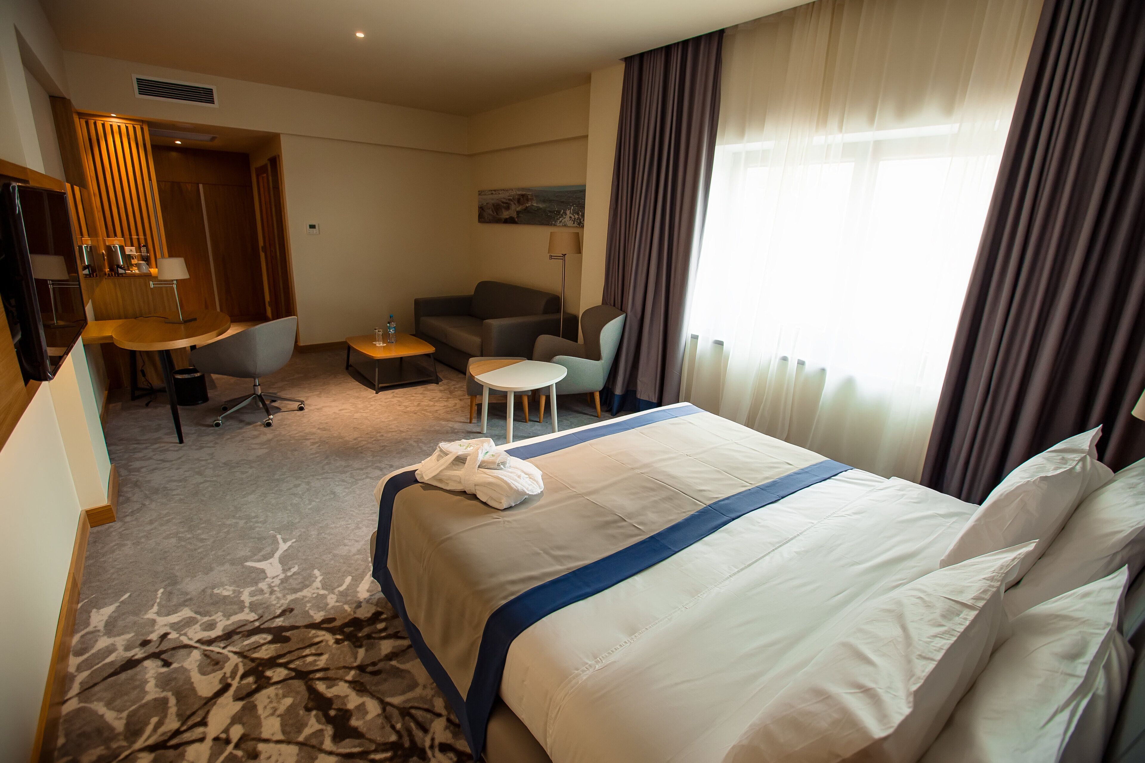 Une chambre d’hôtel avec un grand lit, un bureau, une chaise, une petite table et un canapé.