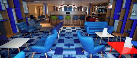 A modern lounge area with seating, a bar, and a patterned carpet.