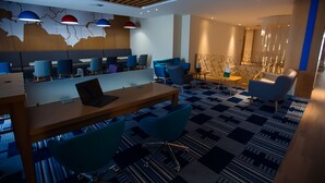 A modern hotel lobby with a wooden ceiling, blue and grey seating, and patterned carpet. - Holiday Inn Aktau - Seaside by IHG (Aktau)