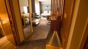 A hotel room with a bed, a desk, a chair, a small table, and a mirror. - Holiday Inn Aktau - Seaside by IHG (Aktau)