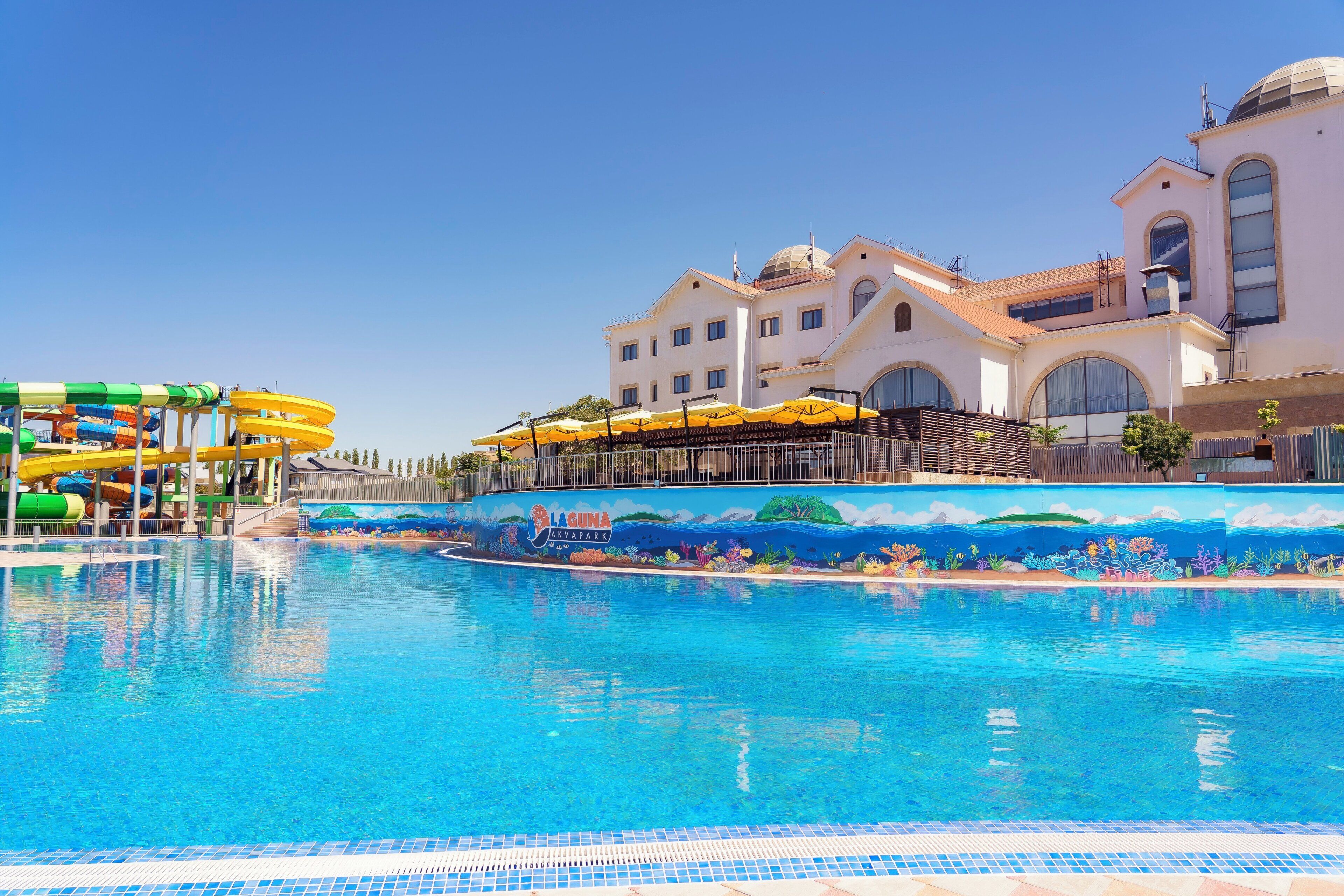 Una piscina con tobogán y un mural que representa una escena submarina.