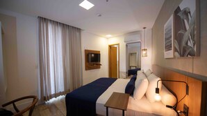 A hotel room with a bed, bedside table, lamp, curtains, and a mirror. - Leblon Design Hotel (Rio de Janeiro)