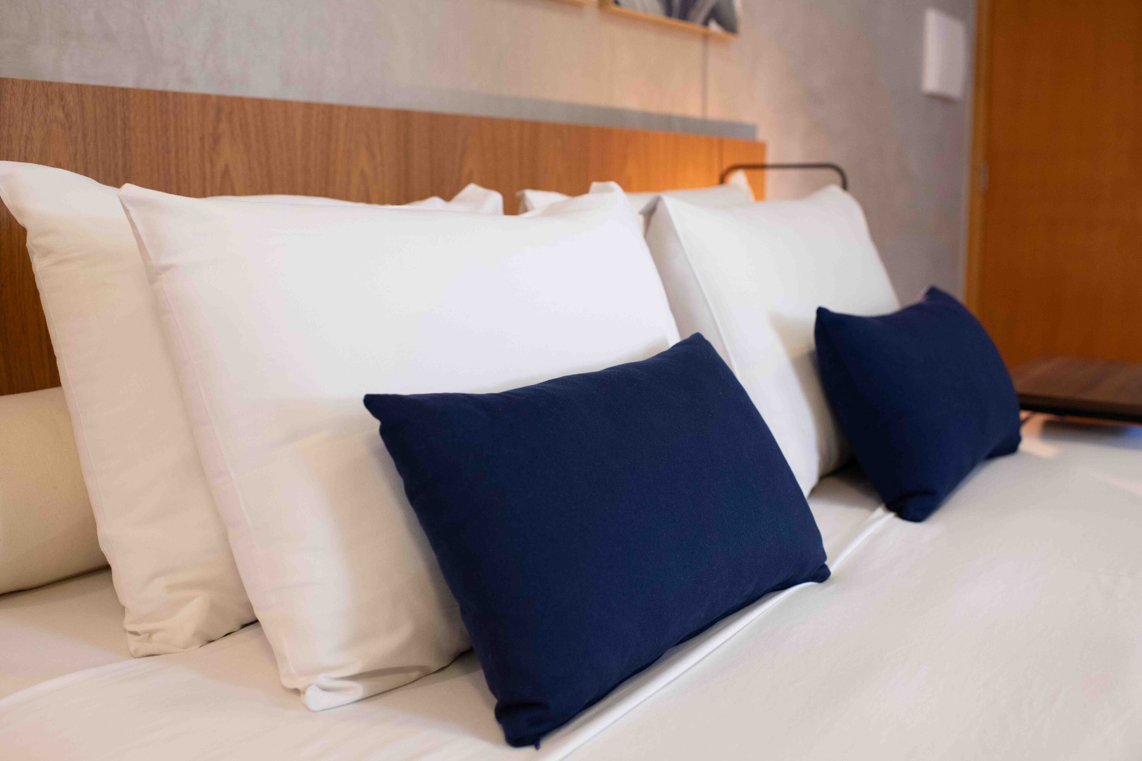 A bed with white and navy blue pillows.