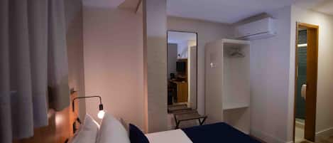 A hotel room with a bed, bedside lamp, wardrobe, and a mirror.