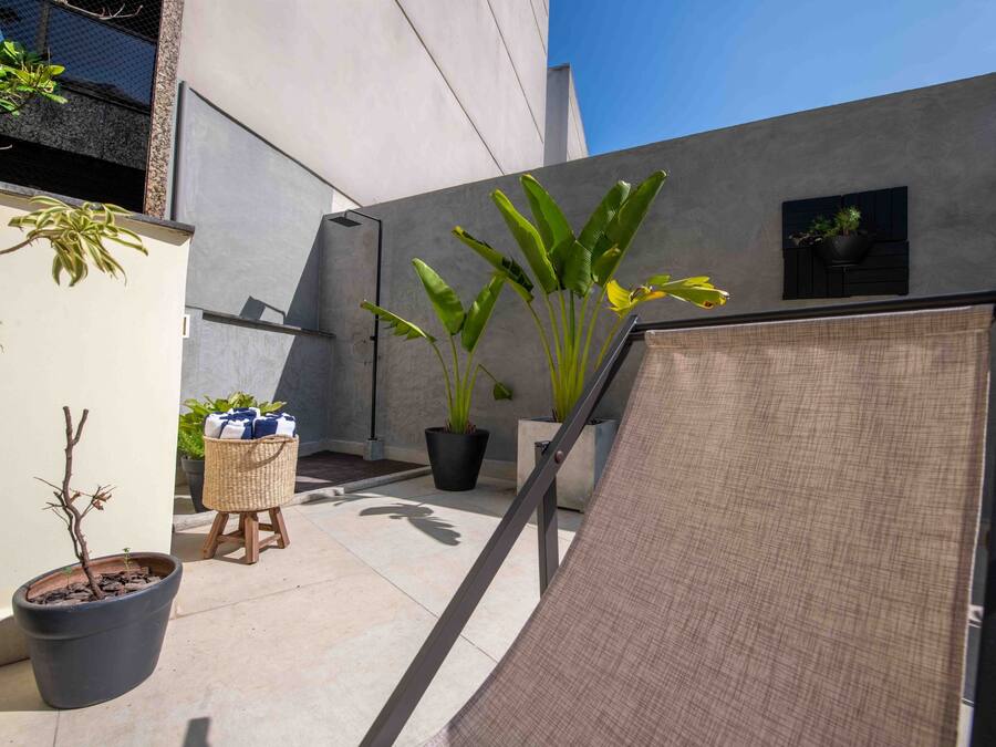 Un espace extérieur moderne agrémenté de plantes en pot, d’une petite table et d’un grand paravent en tissu.