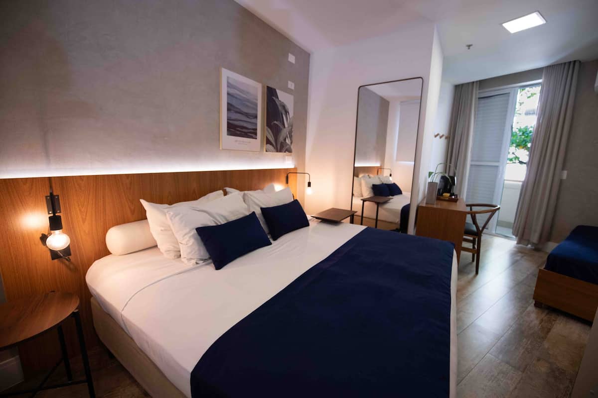 Habitació d'hotel moderna amb un llit gran, taules de nit, escriptori i una cadira.