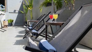A rooftop lounge area with reclining chairs, a table with drinks, and potted plants. - Leblon Design Hotel (Rio de Janeiro)