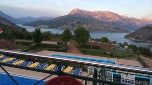 Area piscina con lettini e vista sulle montagne e sul lago.